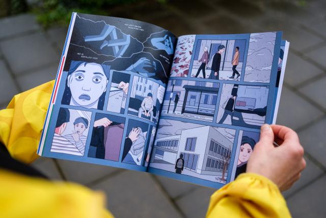 Personne tenant entre ses mains un livre avec des dessins animés.