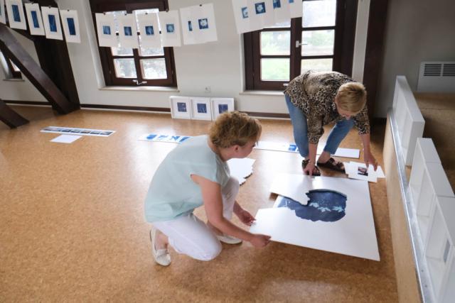 Two women hanging pictures for an exhibition