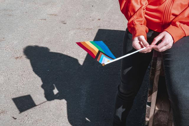  eine Frau hält die Flagge der LGBTIQ+-Gemeinschaft in der Hand