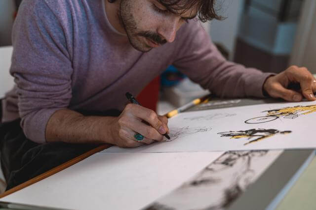 ein Mann arbeitet an einer Illustration an einem Schreibtisch