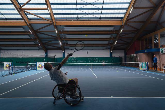 A man in a wheelchair, as he plays tennis.