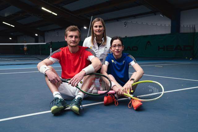 A tennis instructor with a young man and a woman. All three look at the camera.