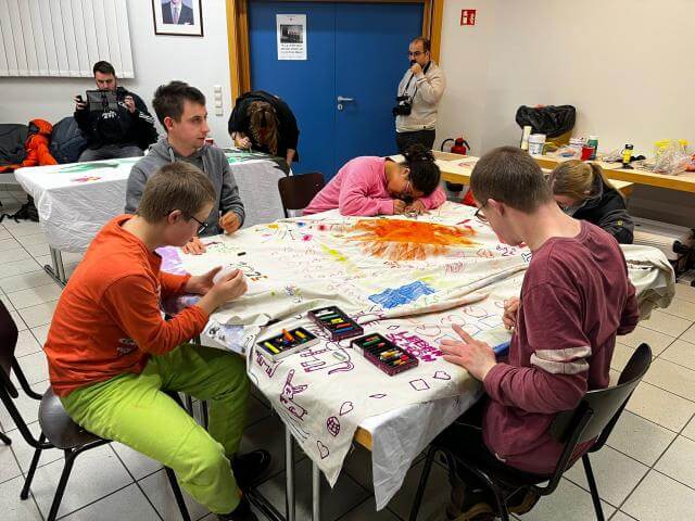 des personnes assises autour d'une table en train de dessiner sur un drapeau
