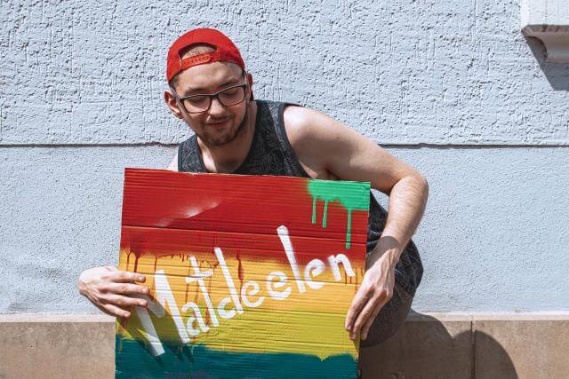 Ein Mann hält ein Schild mit der Aufschrift „Matdeelen“.