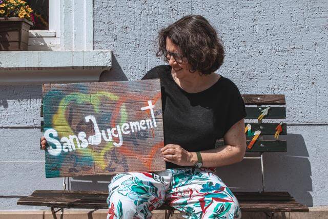 A woman holding a sign with “without judgment” written on it.