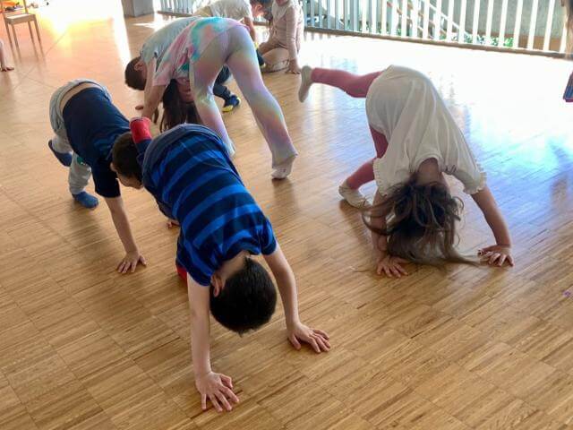 Children doing movement exercises in a rehearsal room.