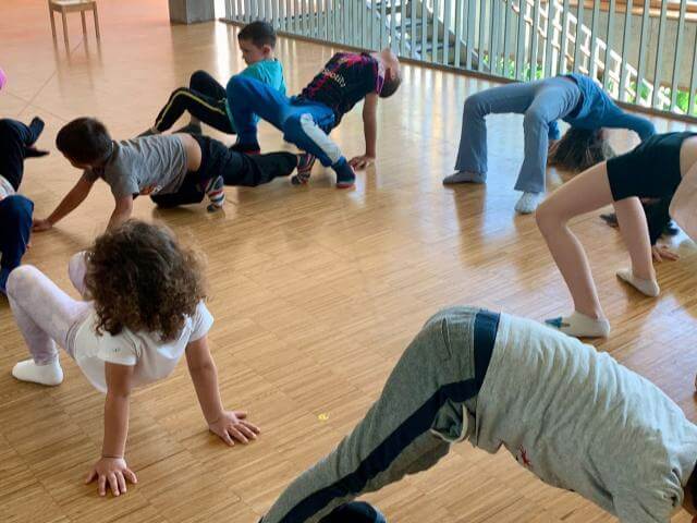Children doing movement exercises in a rehearsal room.