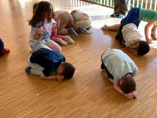 Children doing movement exercises in a rehearsal room.