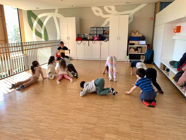 Children doing movement exercises in a rehearsal room.