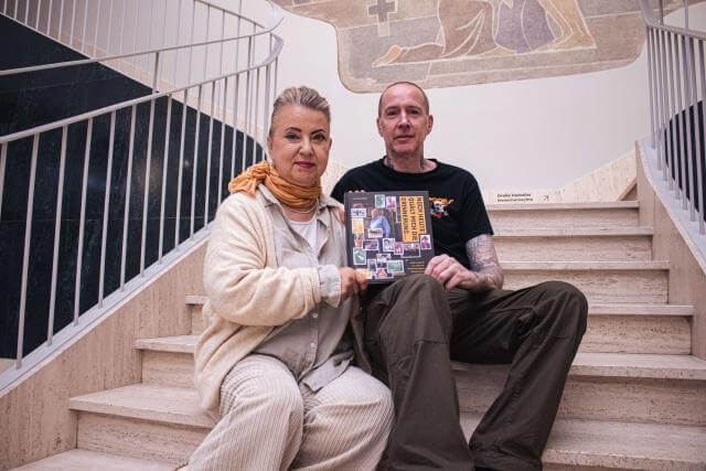 une femme et un homme sont assis sur des escaliers, montrant un livre