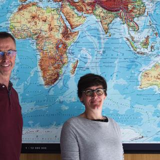 portrait d'un homme et d'une femme devant une carte du monde