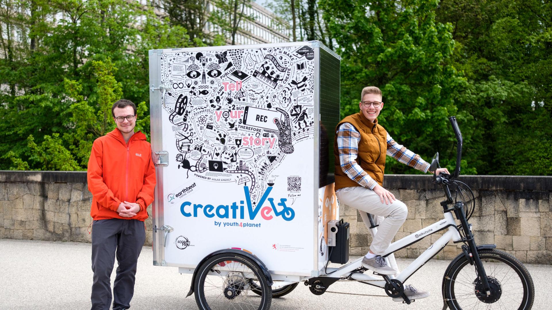 Deux jeunes hommes de l'assciation Youth4Climate, portraités dans un parc avec leur vélo du projet Creativelo.