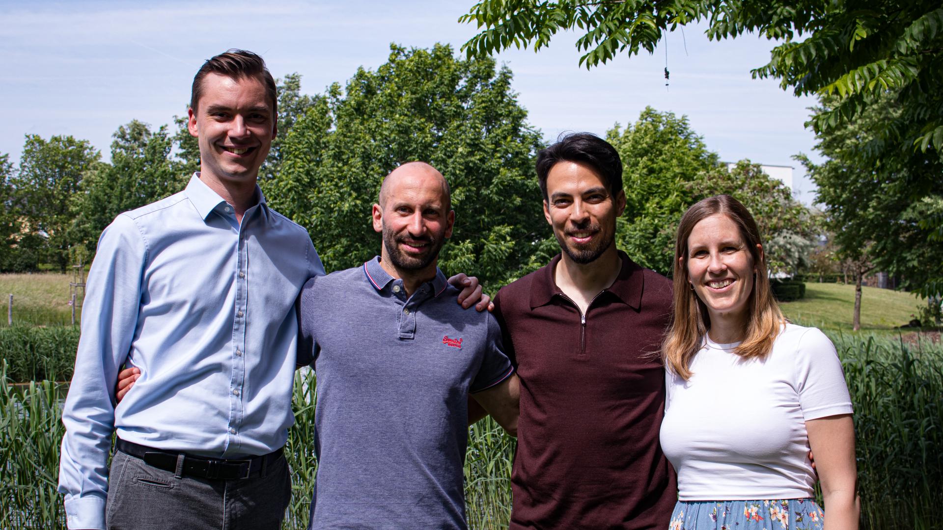 portrait of three men and one woman in front of a little pond