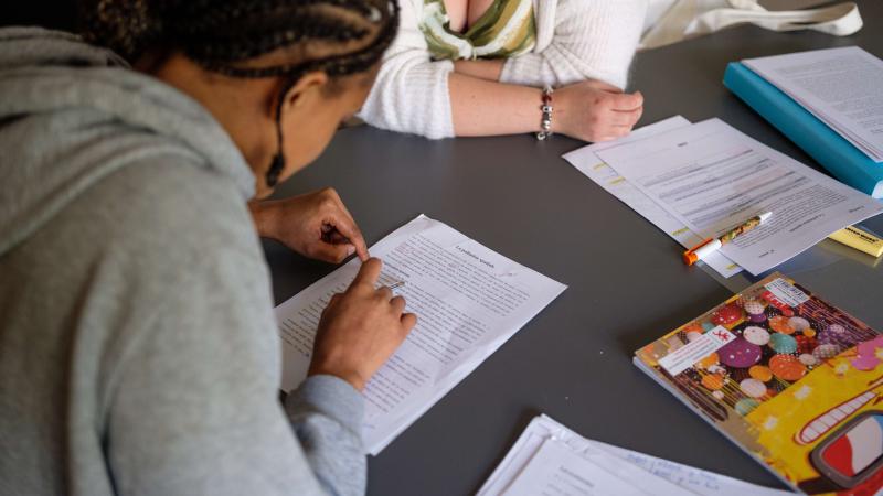 jeune étudiante qui lit un texte sur une feuille. on la voit de dos