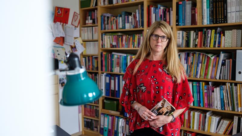 Portrait de Nathalie Esser devant une bibliothèque remplie de livres