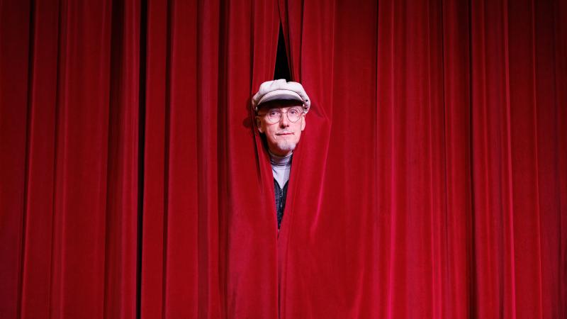 Portrait de Pit Vinandy devant un rideau rouge